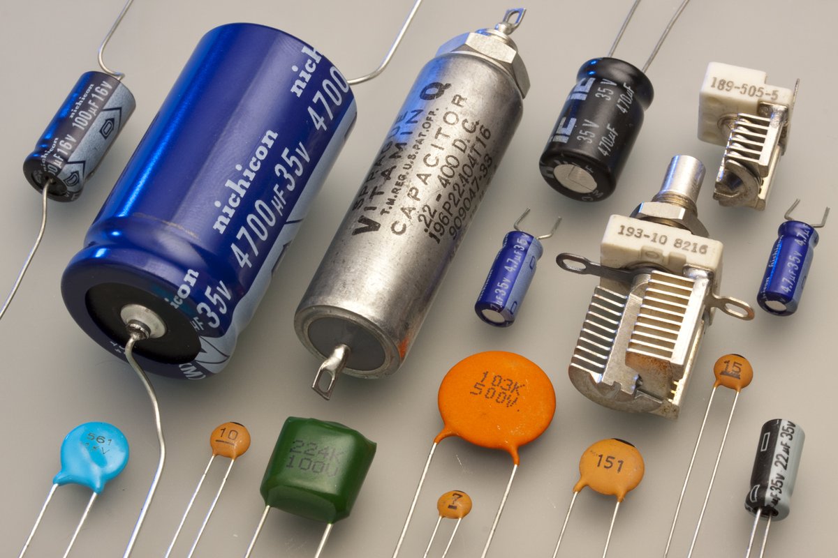 Różne typy kondensatorów elektronicznych — elektrolityczne, ceramiczne, tantalowe i zmienne — wszystkie magazynują ładunek i energię pola elektrycznego. · źródło: Eric Schrader, Wikimedia Commons, CC BY-SA 2.0