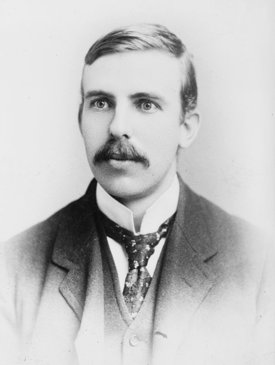 Ernest Rutherford przeprowadził pierwszą sztuczną reakcję jądrową (¹⁴N + α → ¹⁷O + proton); reakcje jądrowe rządzą się zachowaniem liczby nukleonów A i ładunku Z. · źródło: Bain News Service, Wikimedia Commons, domena publiczna
