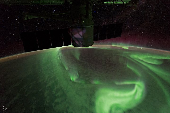 Zorza (aurora australis) sfotografowana z Międzynarodowej Stacji Kosmicznej: cząstki wiatru słonecznego kierowane polem magnetycznym ku biegunom wnikają w atmosferę i wywołują świecenie. · źródło: NASA, Wikimedia Commons, domena publiczna