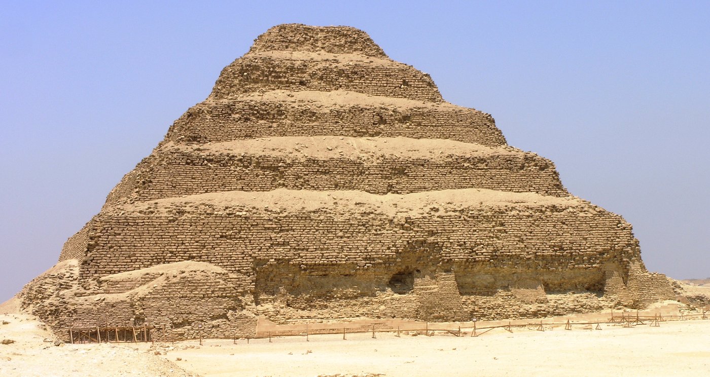 Piramida schodkowa Dżosera w Sakkarze (ok. 2650 p.n.e., arch. Imhotep) — sześć mastab ustawionych jedna na drugiej; „schody do nieba", pierwsza monumentalna budowla z ciosanego kamienia · źródło: Daniel Mayer, Wikimedia Commons, CC BY-SA 3.0
