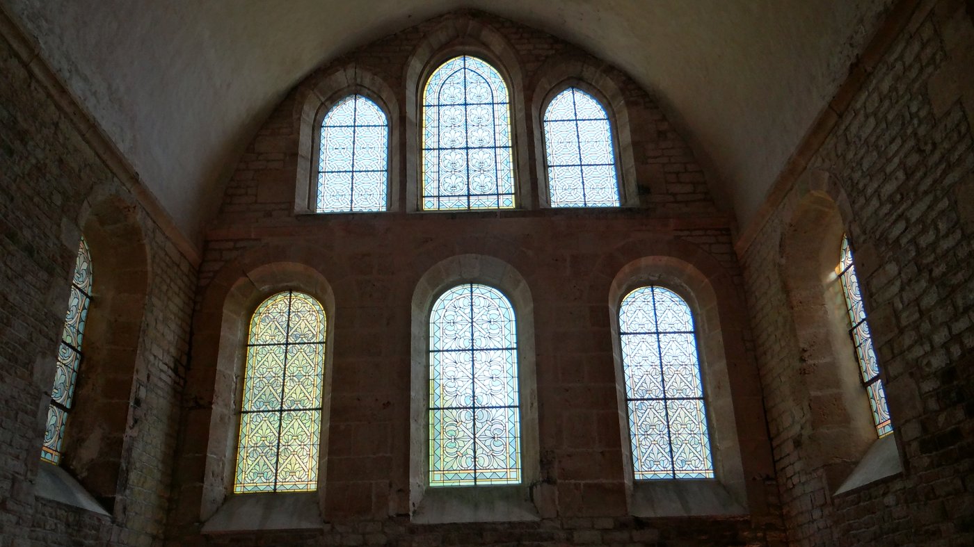 Wnętrze opactwa cysterskiego Fontenay (ok. 1139–1147) — ascetyczna surowość: brak rzeźby figuralnej i złoceń, w oknach tylko jasne szkło ornamentalne (grisaille) zamiast barwnych witraży z postaciami; siła czystych proporcji i nagiego kamienia · źródło: Ibex73, Wikimedia Commons, CC BY-SA 4.0