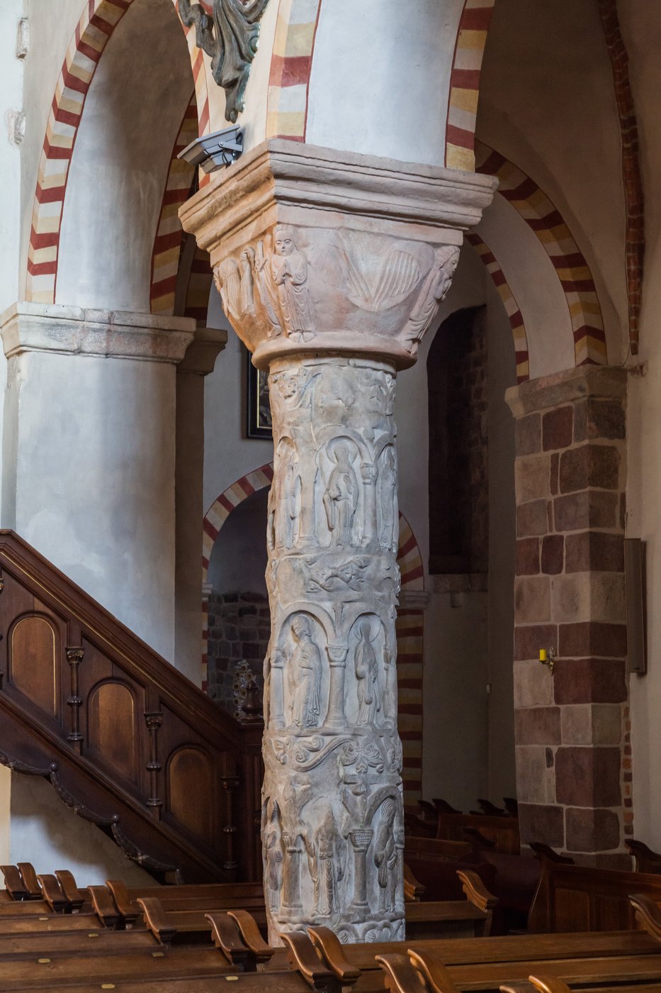 Kolumna Cnót z kościoła Trójcy Świętej w Strzelnie (ok. 1160–1180) — personifikacje cnót w pasach na trzonie; kolumna dosłownie „dźwiga" Kościół · źródło: Pko, Wikimedia Commons, CC BY-SA 4.0