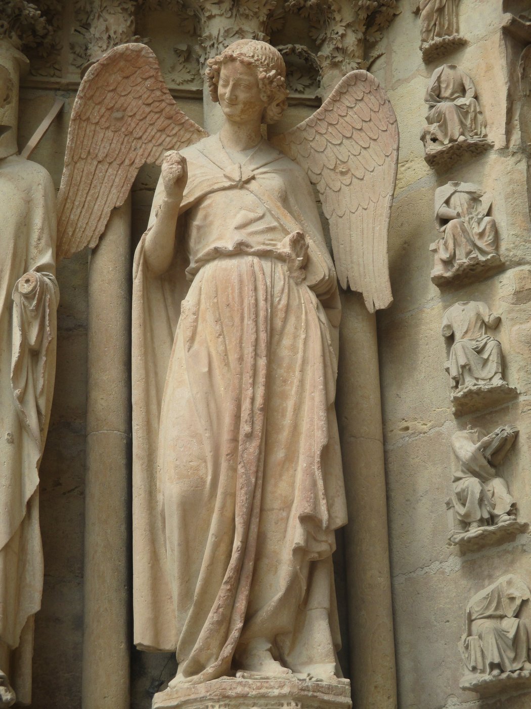„Uśmiech Anioła" z katedry w Reims (ok. 1236–1245) — delikatny, niemal ludzki uśmiech, miękko opadające szaty, lekki kontrapost; dojrzały naturalizm gotycki · źródło: Thomon, Wikimedia Commons, CC BY-SA 4.0